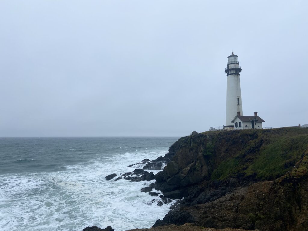 Waves of the pacific ocean crash below pigeon point light station state historic park on the California coast in a winter storm