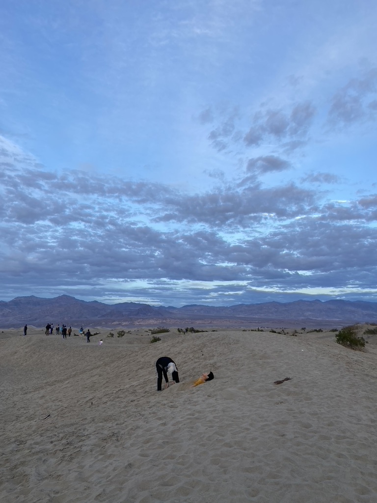 During a winter Sunset at Mesquite Flat Dunes of Death Valley National Park a father buries his son in sand