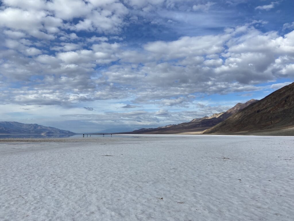 Blue winter skies with a few white clouds above white salt flats in Death Valley National Park California